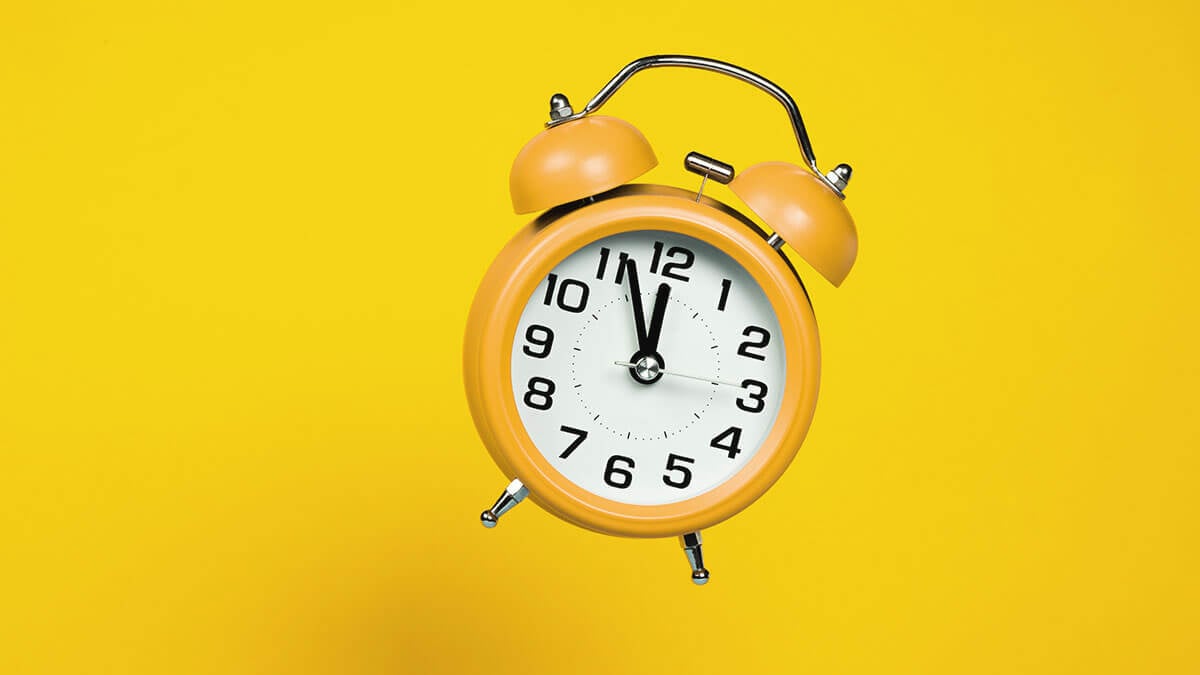 Yellow alarm clock on a yellow background.