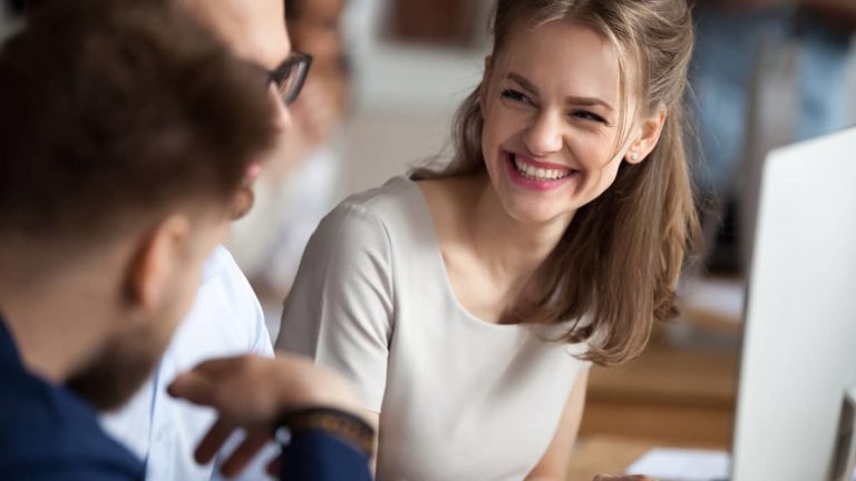 Woman looking at two co-workers and laughing.