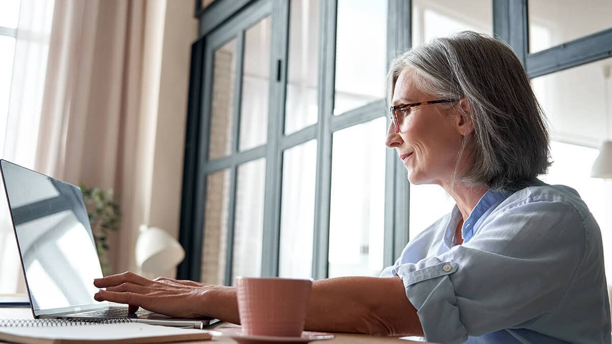 Older woman at a desk using a laptop.