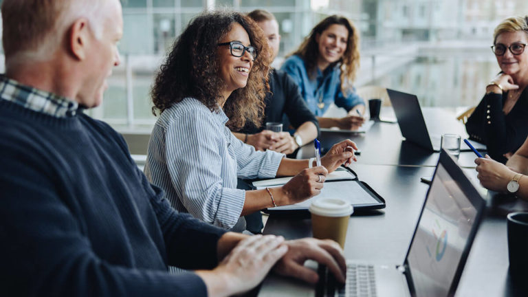 Smiling employees sitting around a table.