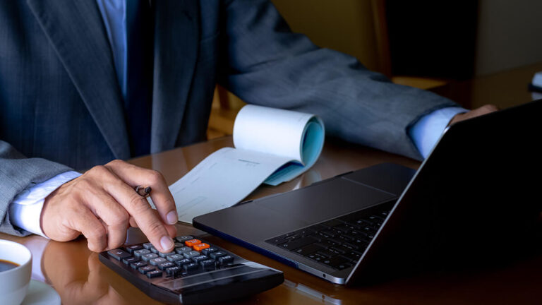 Man using calculator and preparing to write a paycheck.