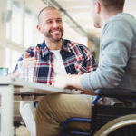 Business owner talking with an employee in a wheelchair.