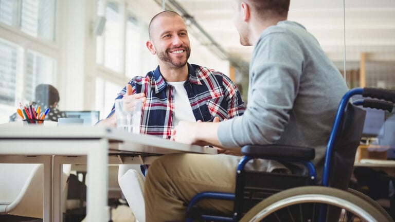 Business owner talking with an employee in a wheelchair.