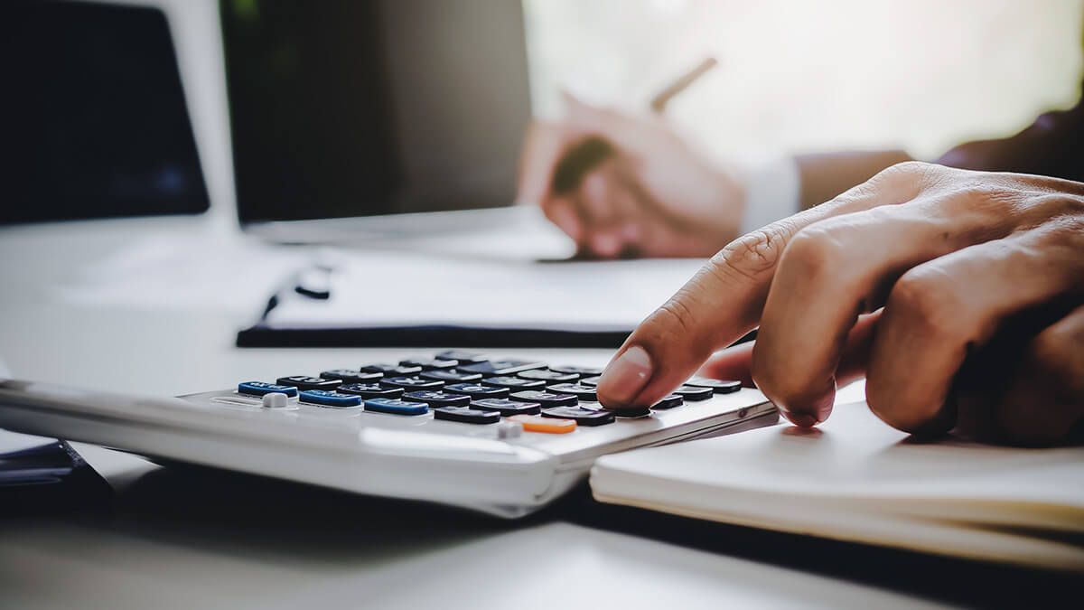 Business owner calculating net profit on calculator.