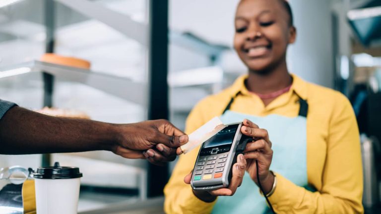 saleswoman holding credit card machine as customer pays a price based on markup percentage