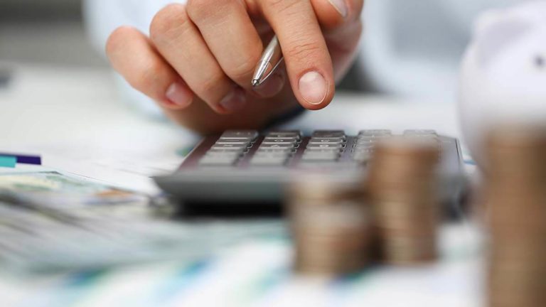 Employer calculating payroll deductions on a calculator.
