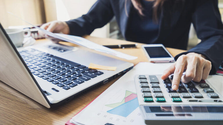 Business owner using calculator and laptop.