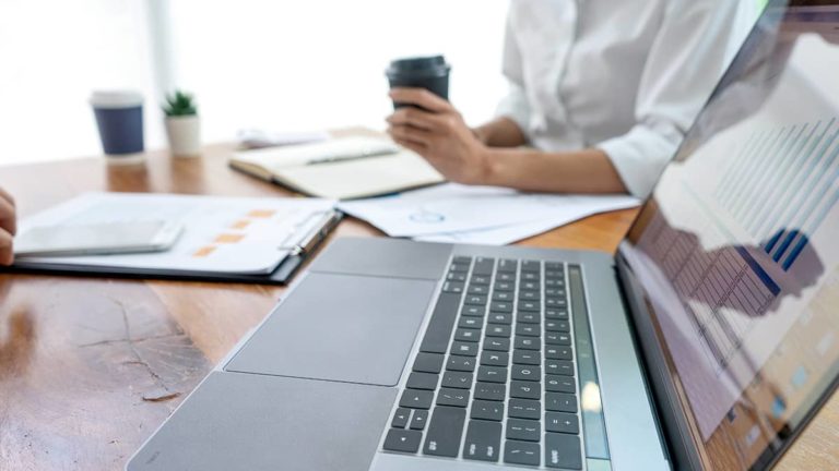 Laptop and a business owner holding a cup of coffee.