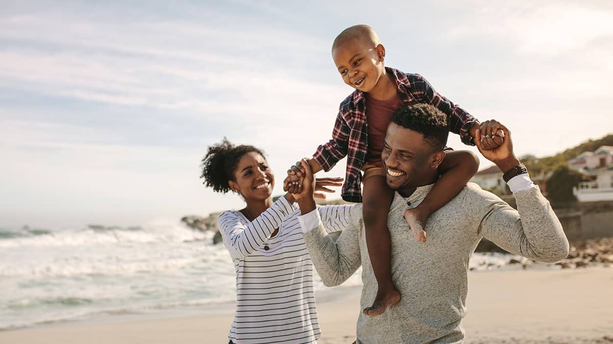 Family of three walking on the beach.