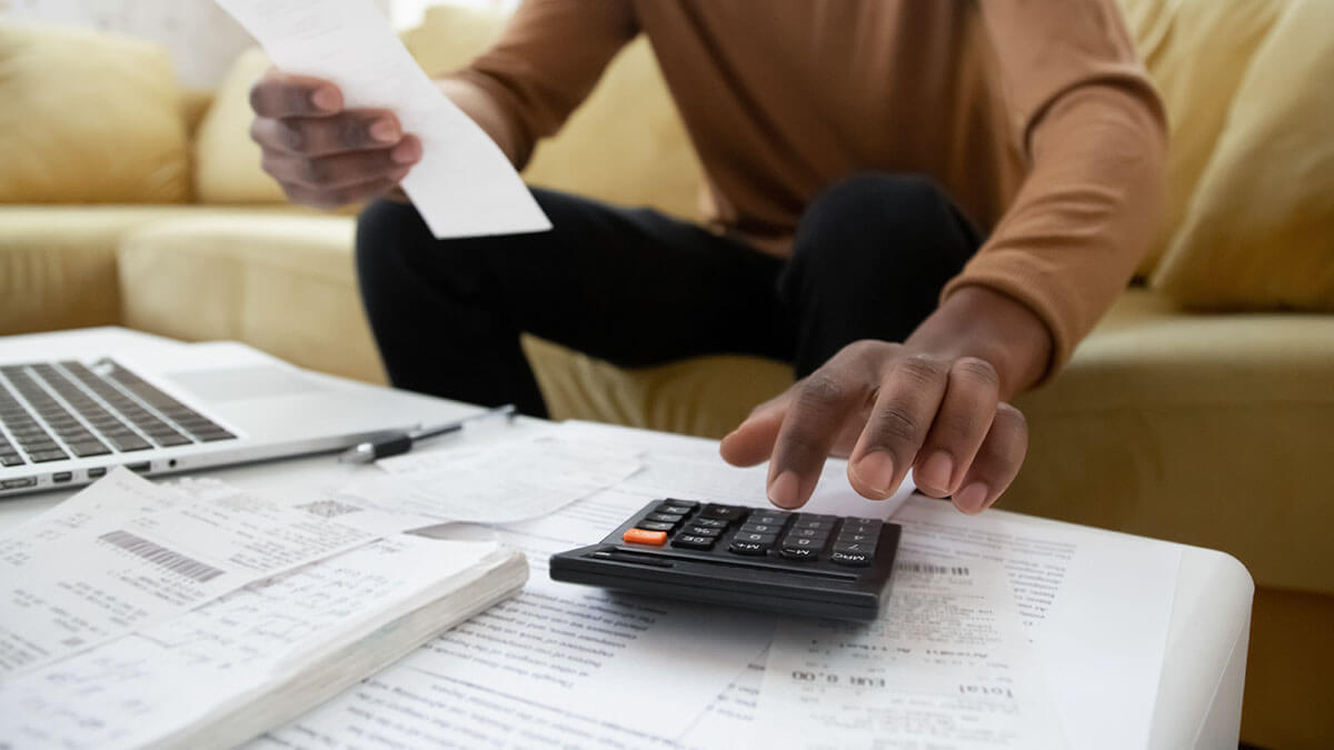 Man holding a receipt and using a calculator.