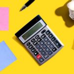 Calculator, post-it notes and piggy bank on a yellow background.