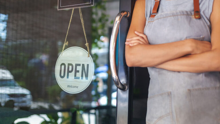 Business owner standing in front of an "Open" sign.