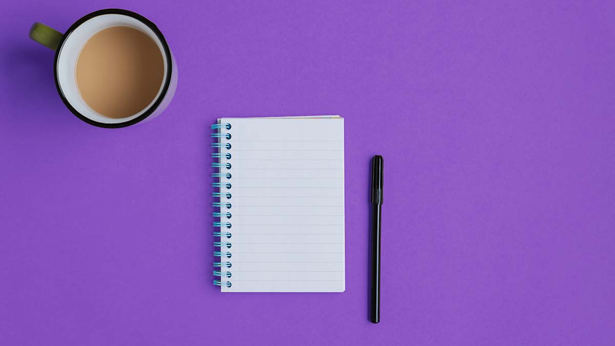 Notebook, pen, and coffee on a purple background.