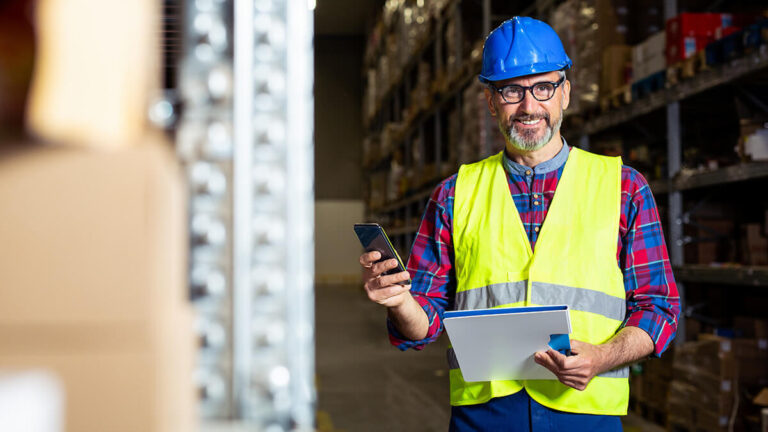 Smiling construction worker holding an envelope and phone.