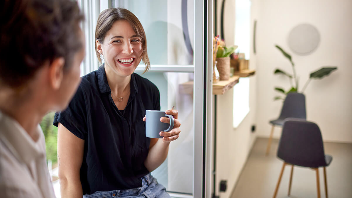 Laughing employee holding a blue mug of hot chocolate.
