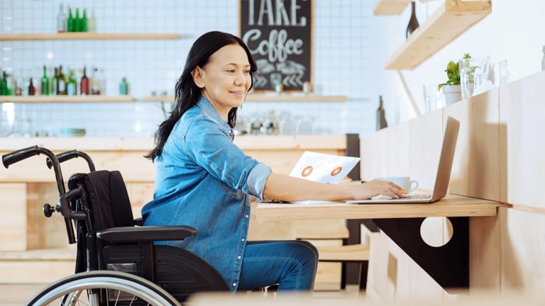 woman sitting in a wheelchair as she works at her desk