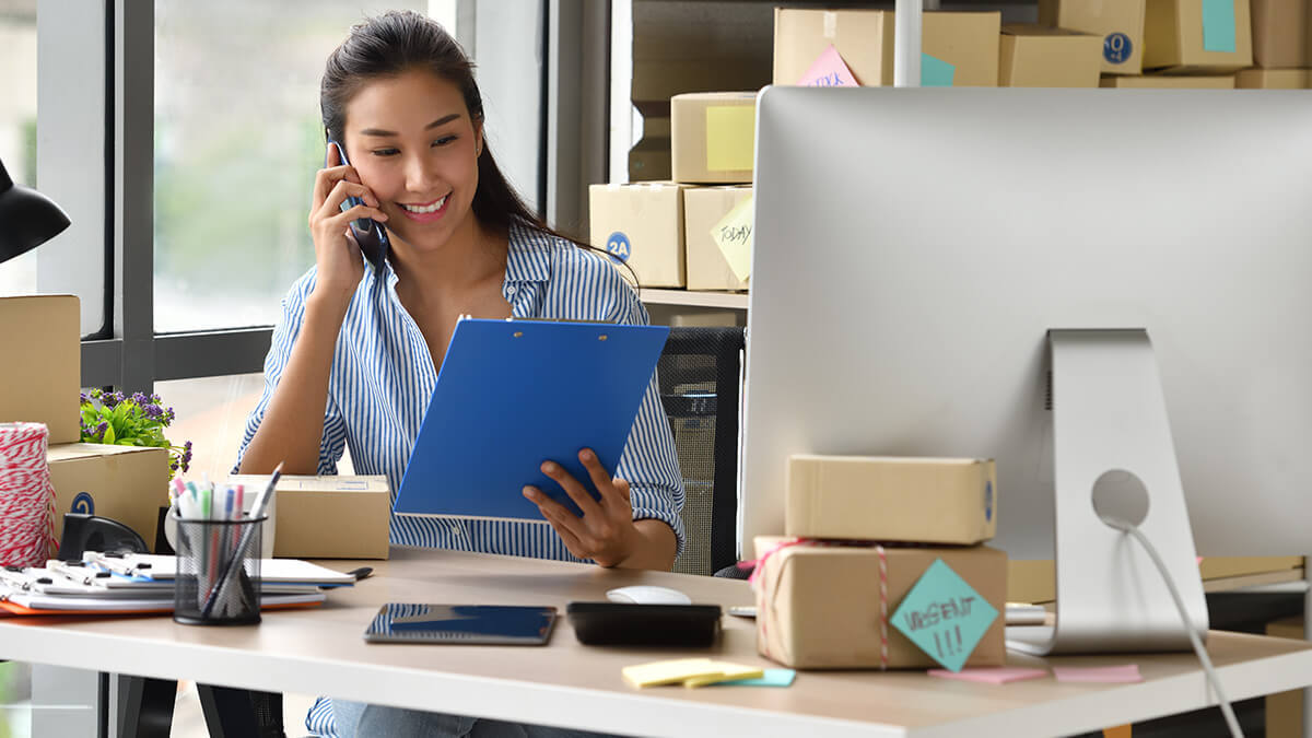 Business owner on the phone looking at a clipboard.