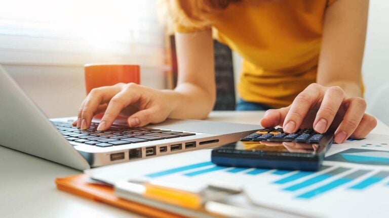 Woman using a calculator and laptop.