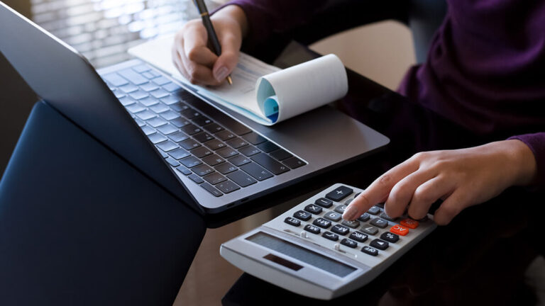 Business owner using a calculator and writing a check.