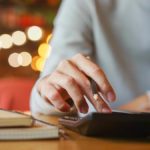 Woman using a calculator. Twinkling lights in the background.