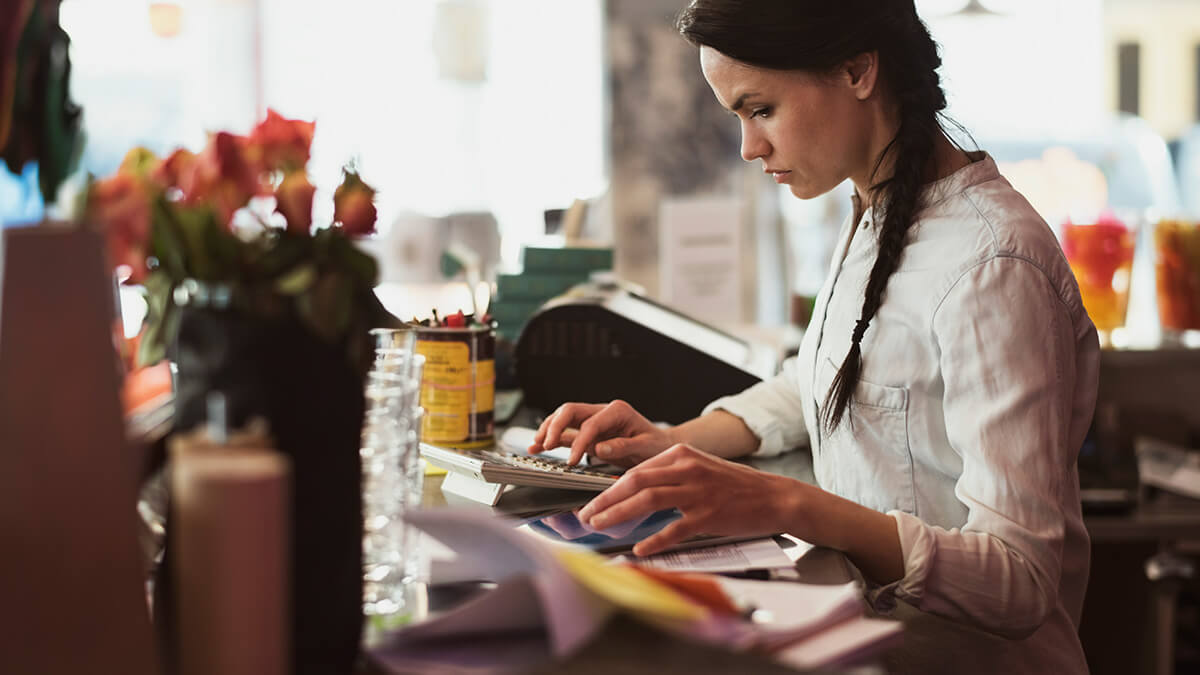 Woman using a calculator near the cash register.