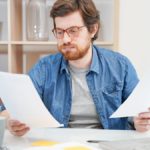 man deciding how to calculate a raise by looking at papers