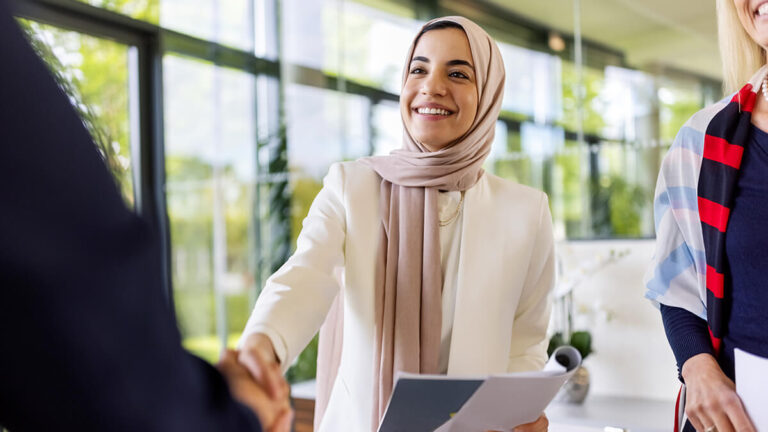 Smiling woman shaking hands with another woman.