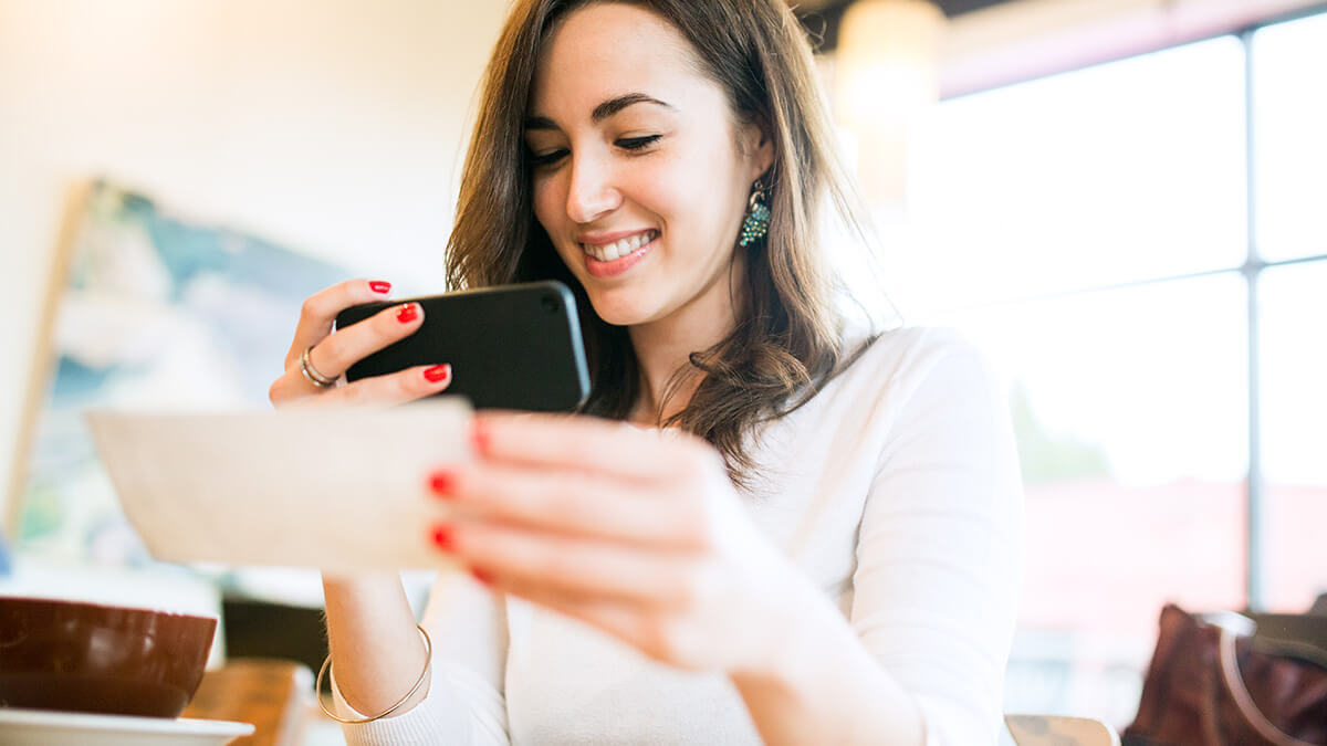 Smiling woman taking a picture of a check.