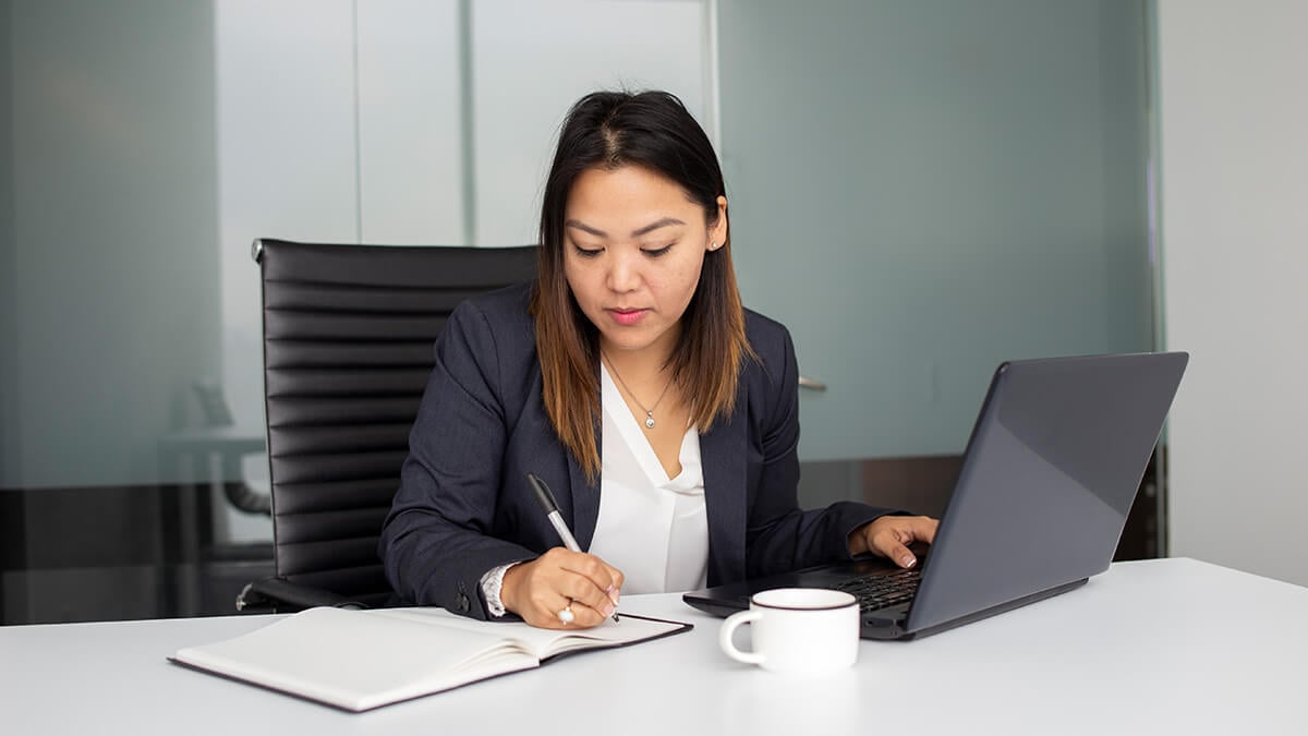 Woman using a laptop and completing paperwork.