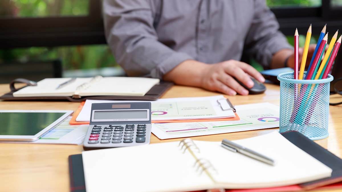 Calculator, pencils, and papers on a desk.