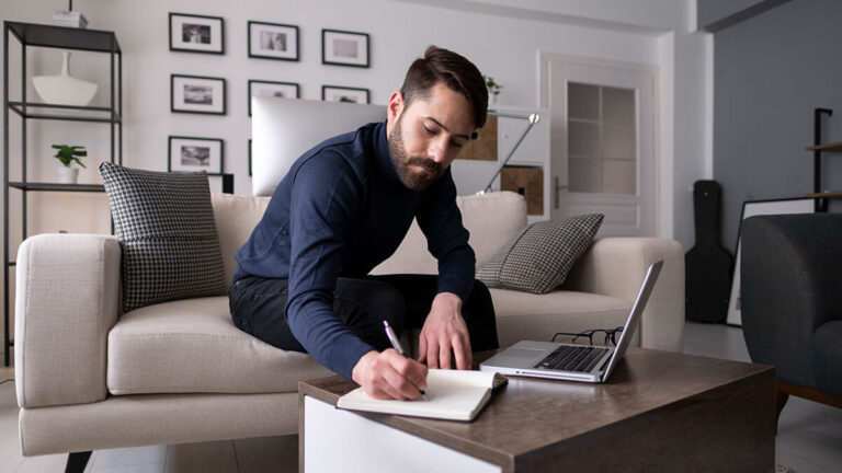 Man sitting on the couch jotting down payroll history.