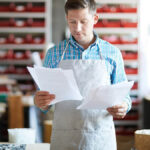 Man in apron reviewing his small business tax liability.