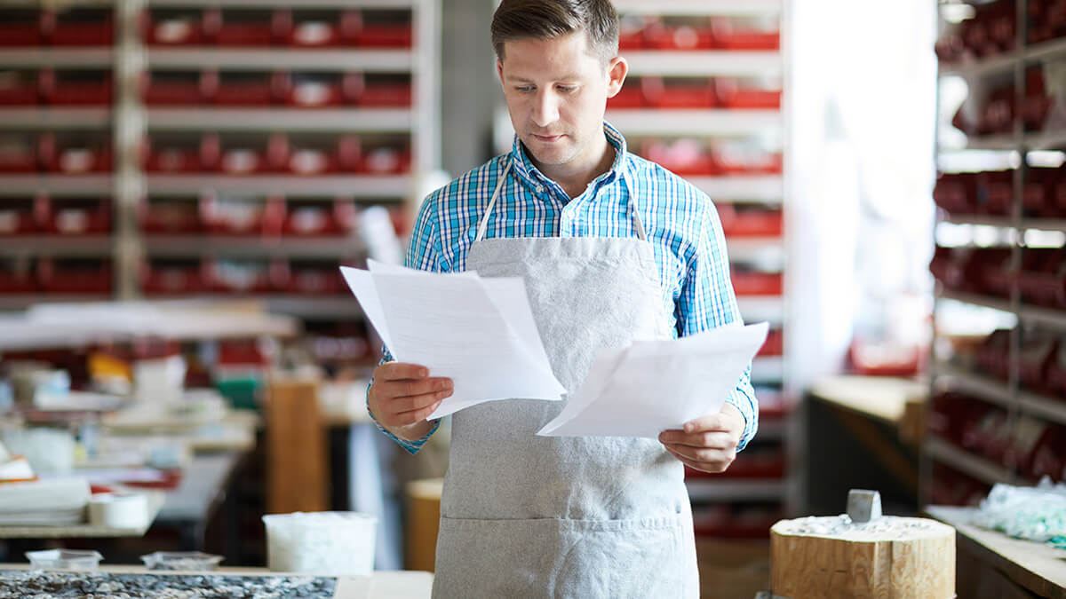 Man in apron reviewing his small business tax liability.