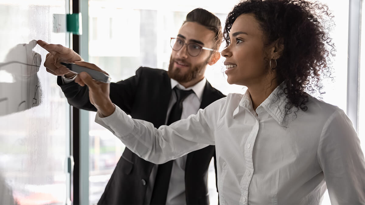 Co-workers looking at accounting terms on a whiteboard.