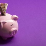 Pink piggy bank with a bill sticking out.