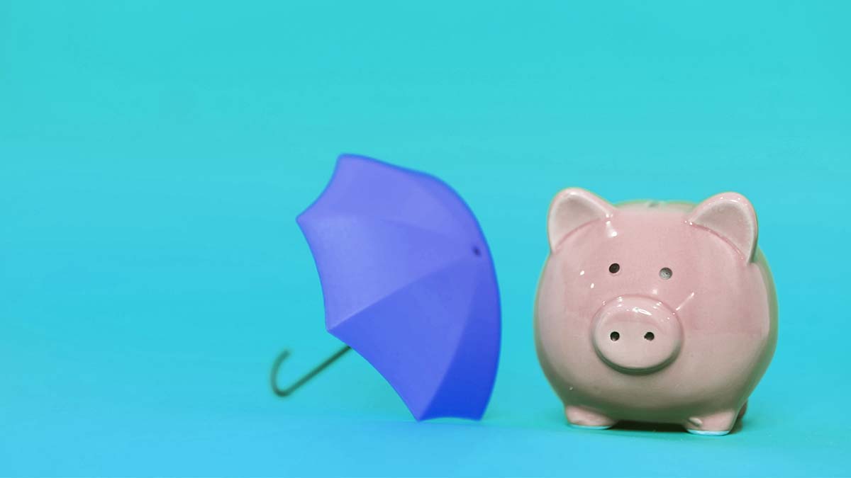 Pink piggy bank next to a tiny umbrella.