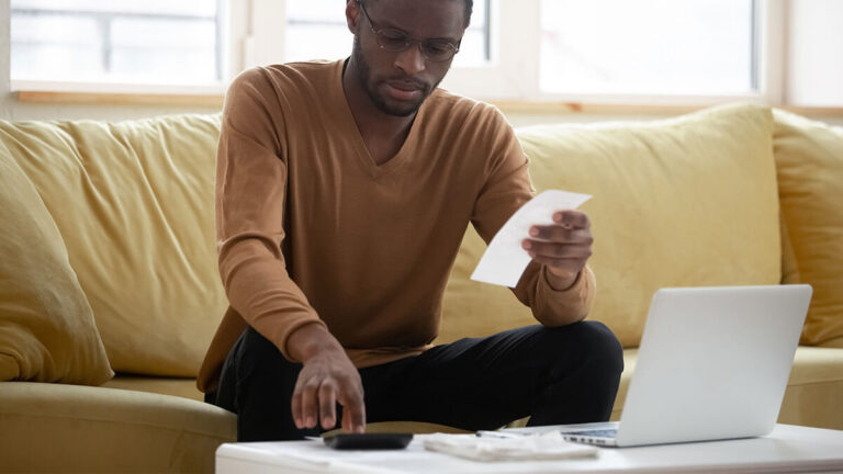 Man holding a receipt and using a calculator.