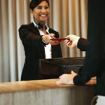 Flight attendant handing passport to traveler.