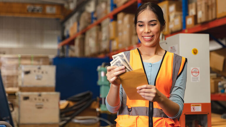 Woman in a warehouse holding cash.