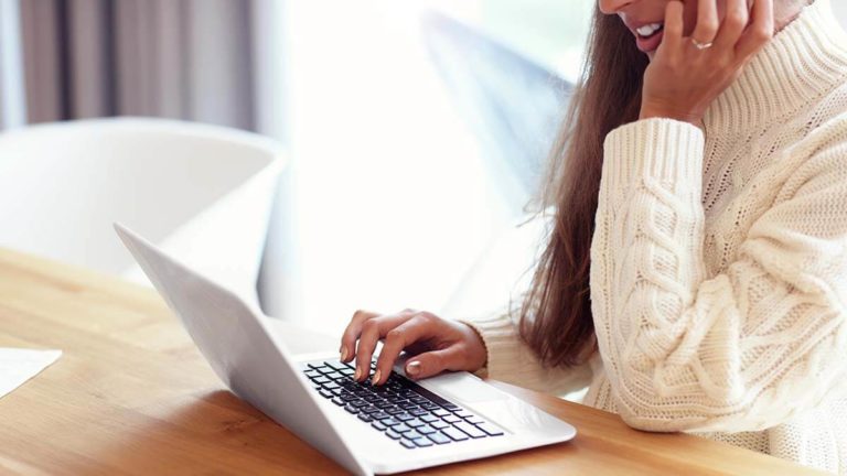 Woman filling out Form 943 on laptop.