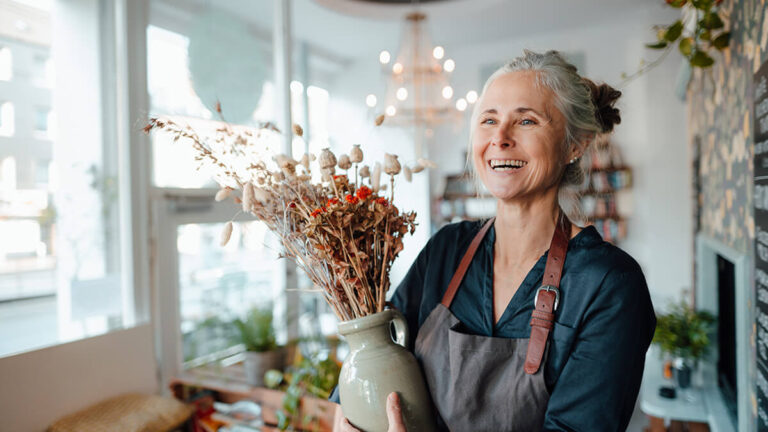 Florist holding a vase with dried flowers.