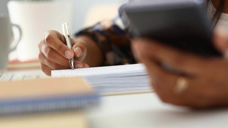 Person using a calculator and writing.