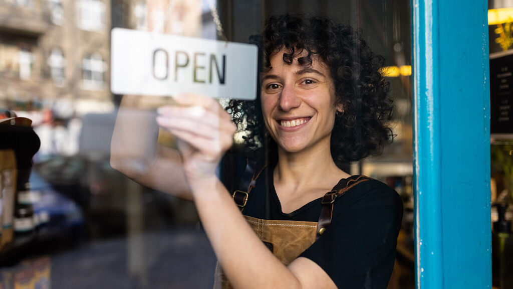 Business owner hanging an "Open" sign on business door.