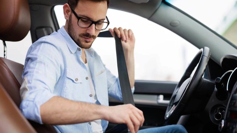 Man buckling his seat belt in the car.