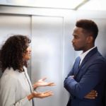 Woman talking with a man in an elevator.