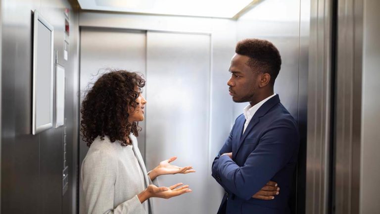 Woman talking with a man in an elevator.