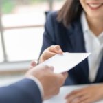 woman handing employee their final paycheck to comply with pto payout laws by state