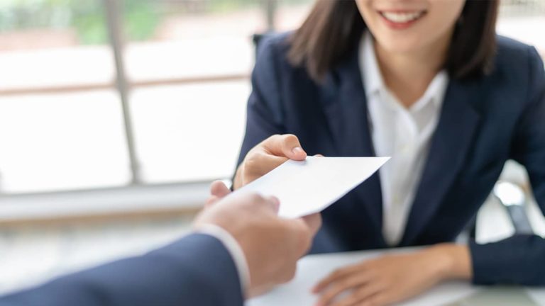woman handing employee their final paycheck to comply with pto payout laws by state