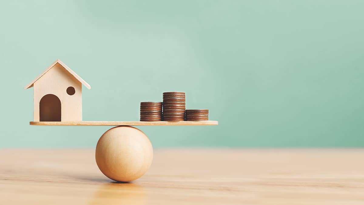 House and coins on a balance ball.