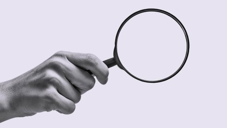 Hand holding a magnifying glass.